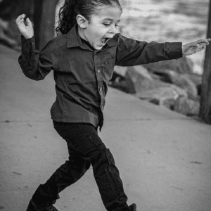 Black and white photo of toddler boy running on a sidewalk