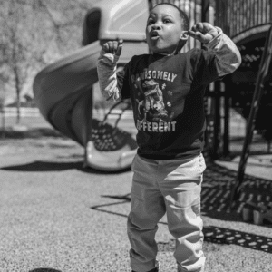 Black and white photo of toddler boy jumping at the park