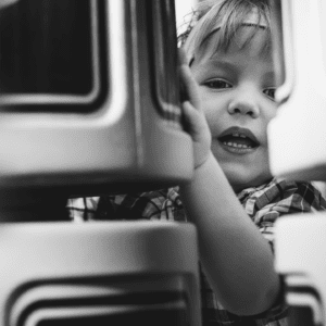 Black and white photo of an infant boy looking between playground equipment