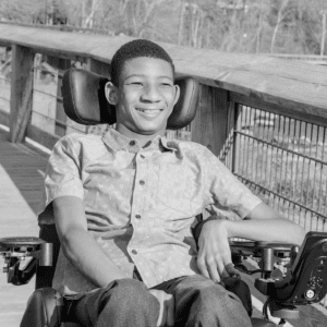 Black and white photo of young adult male in a wheelchair on a bridge