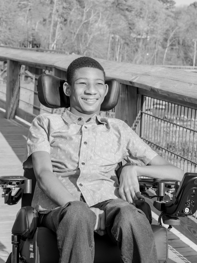 Black and white photo of young adult male in a wheelchair on a bridge