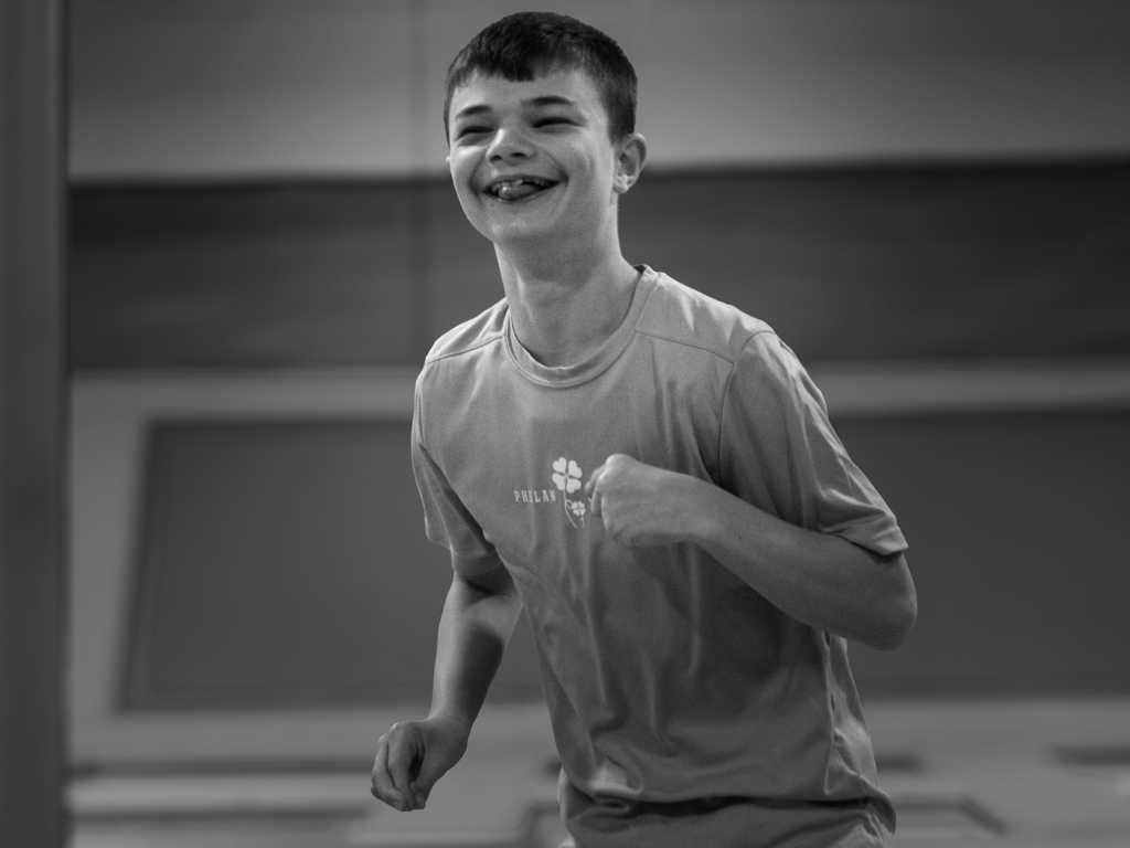 Black and white photo of a young adult male playing in a trampoline park