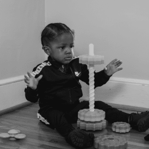 Black and white photo of a toddler playing with toy on the floor
