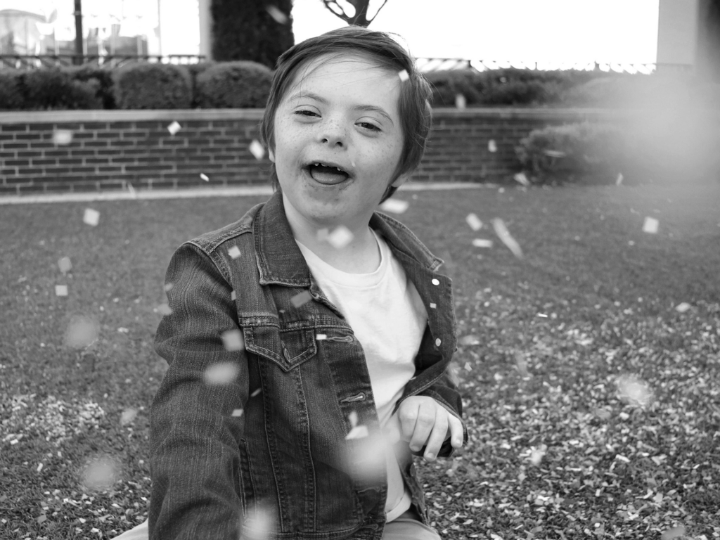 Black and white photo of male child playing in confetti outside