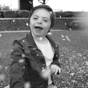 Black and white photo of male child playing in confetti outside