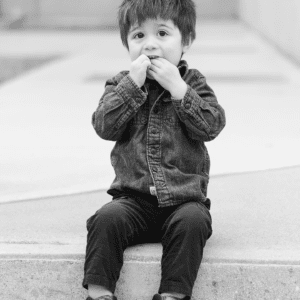 Black and white photo of male toddler sitting on step