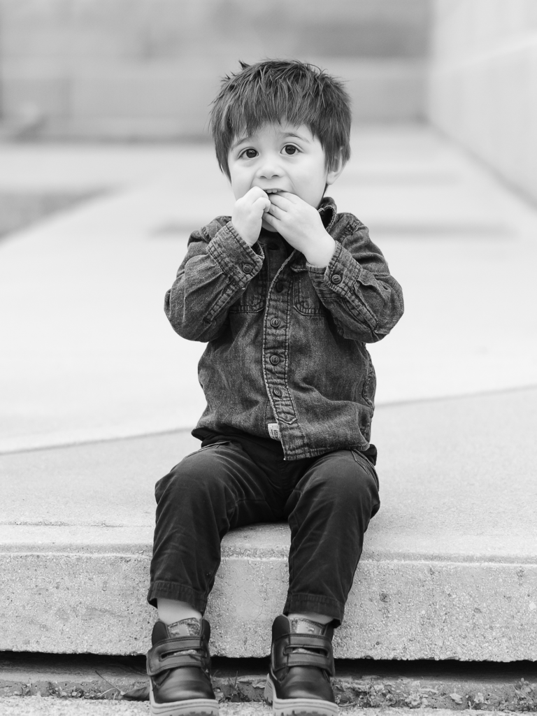 Black and white photo of male toddler sitting on step