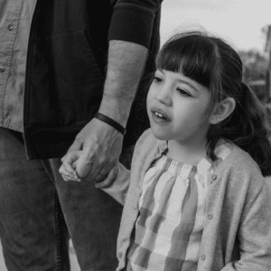 Black and white photo of female child holding a parent’s hand