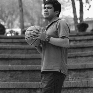 Black and white photo of young adult male playing basketball outside
