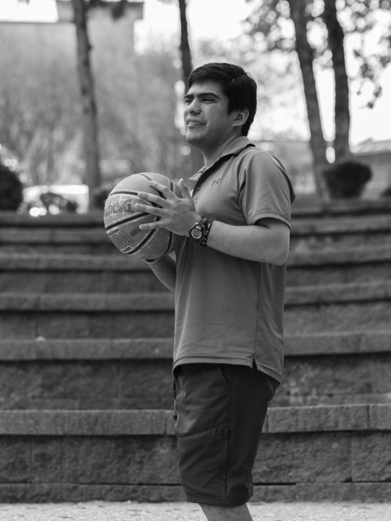 Black and white photo of young adult male playing basketball outside