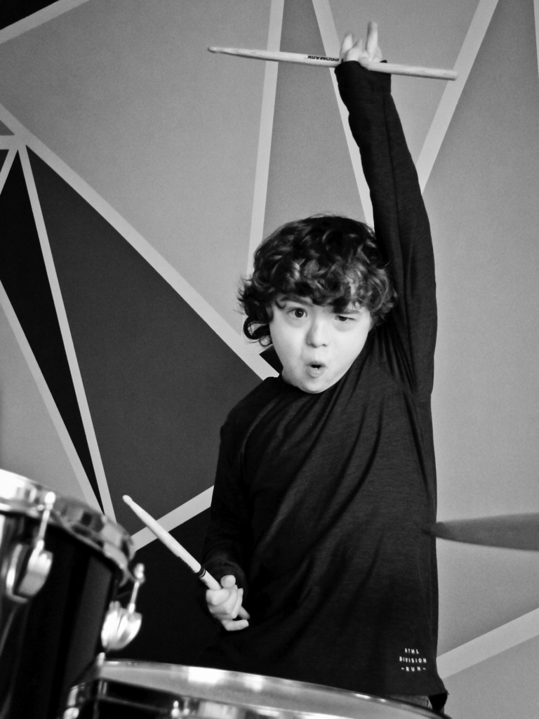 Black and white photo of male child playing the drums
