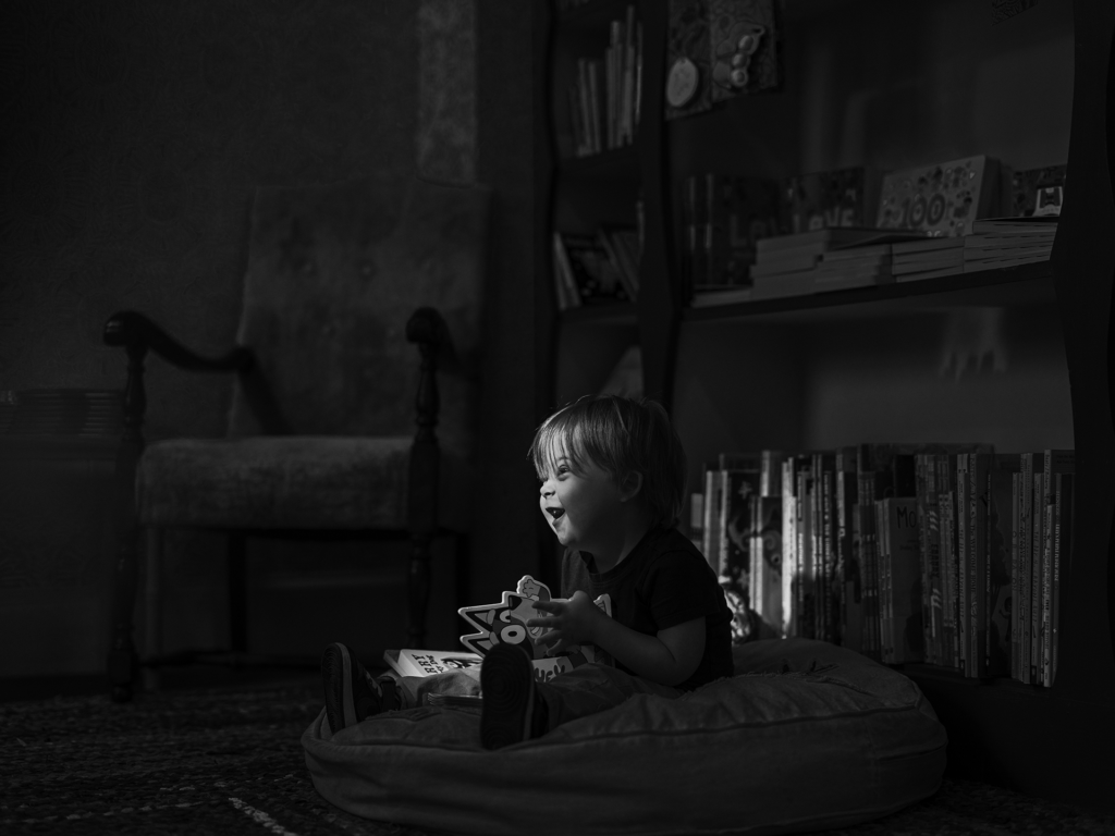 Black and white photo of male toddler reading in a library