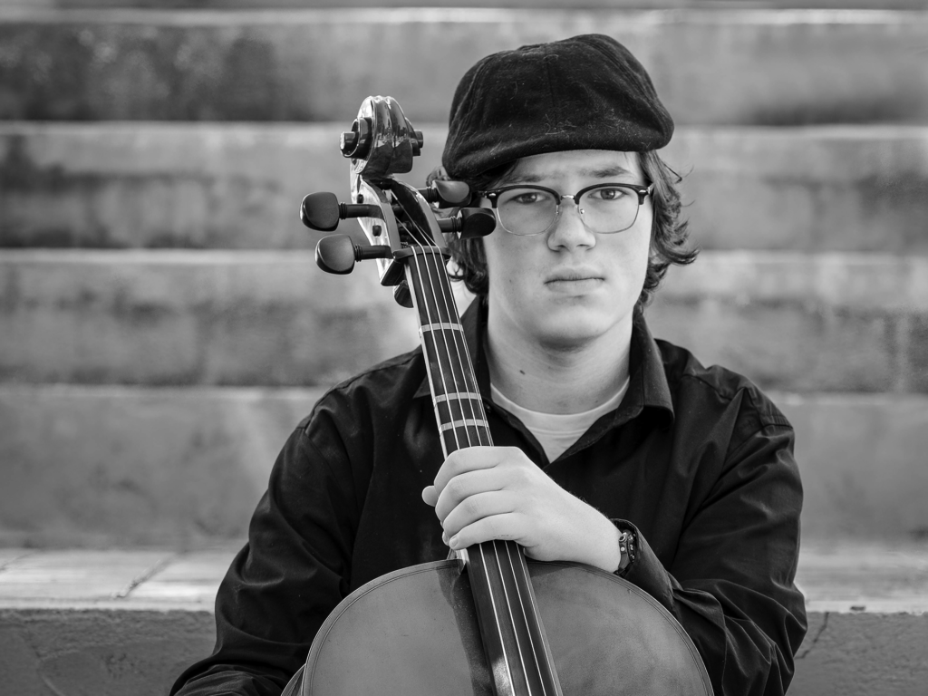 Black and white photo of young adult male playing the cello