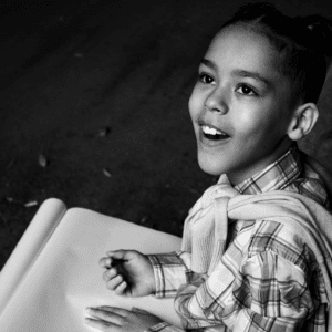 Black and white photo of female child smiling looking up and holding paper
