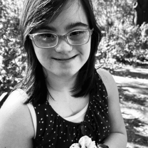 Black and white photo of young adult female holding a flower outside