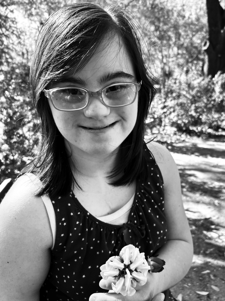 Black and white photo of young adult female holding a flower outside